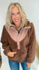 Woman wearing a brown fleece pullover with a sheer panel over a white background