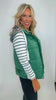 Woman wearing a green puffer vest over a striped shirt against a white background