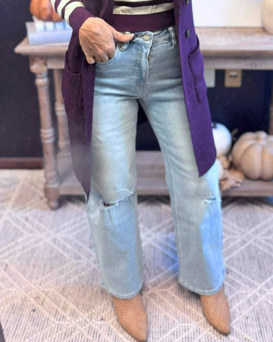 Person wearing light blue jeans and a purple coat indoors.