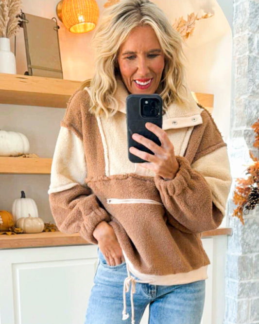 Woman taking a selfie in a cozy indoor setting with pumpkins and decorative lights.