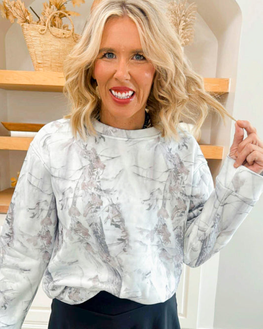 Woman wearing a marble-patterned blouse in a home setting