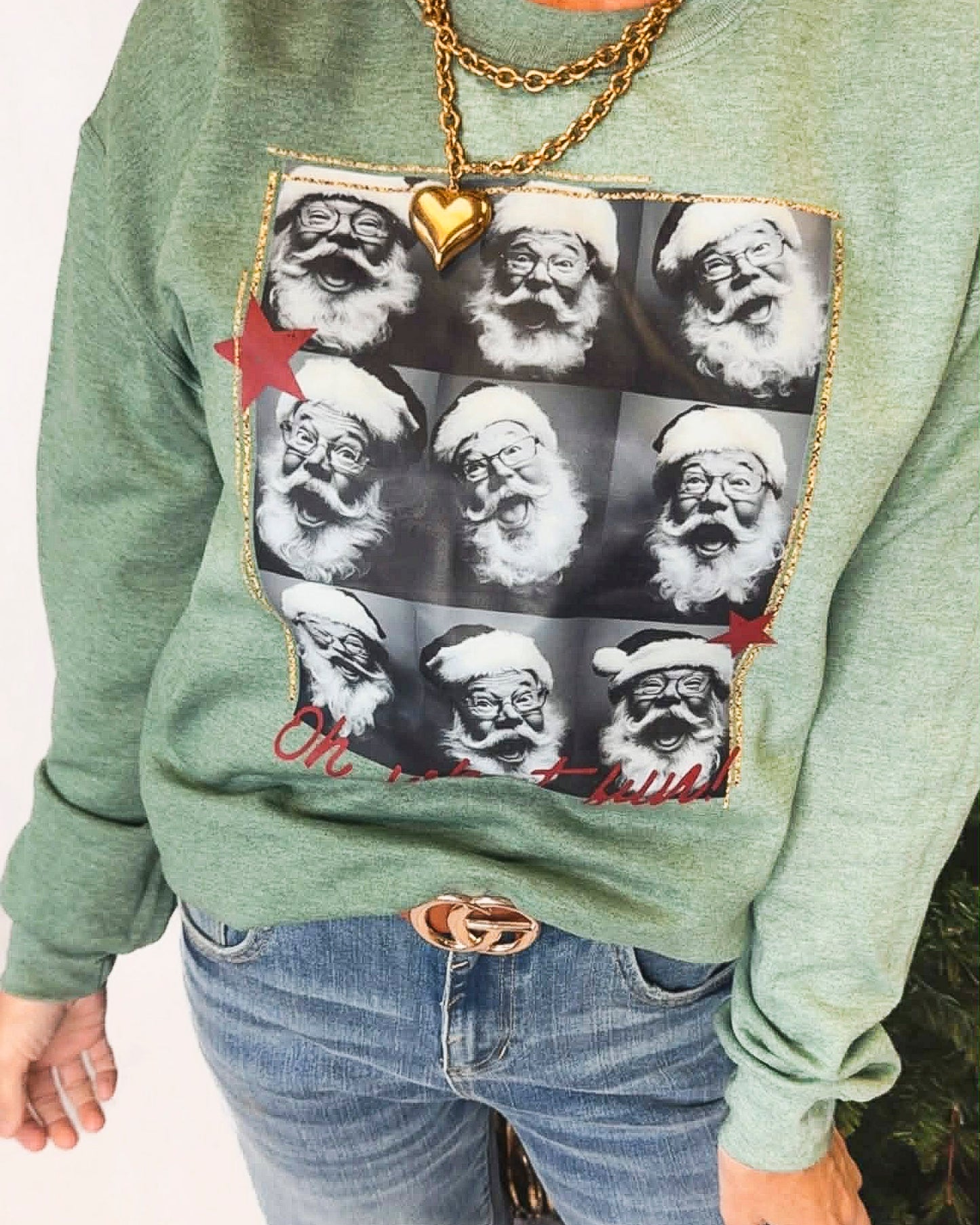 Green sweatshirt with a pattern of Santa Claus faces and a gold chain detail.