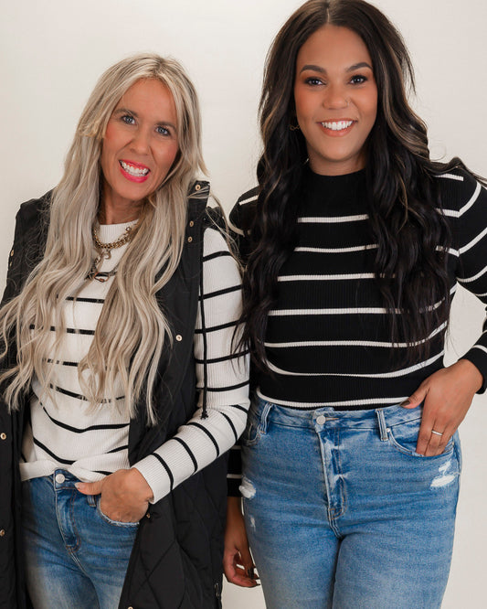 Two women wearing black and white striped shirts with jeans against a plain background
