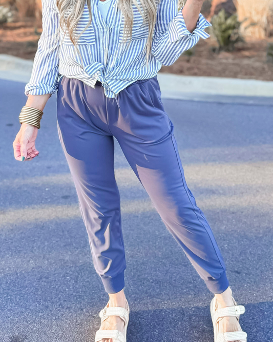 Person wearing a blue and white striped shirt and blue pants on a road.