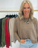 Woman wearing a brown sweater with a rack of sweaters in the background