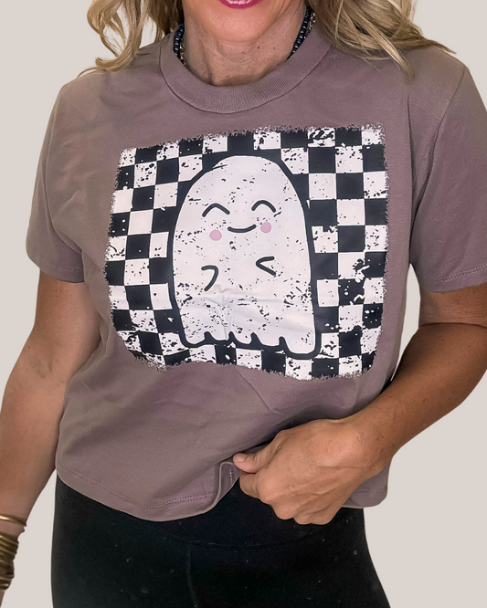 Person wearing a brown t-shirt with a cartoon ghost design on a checkered background