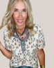 Woman wearing a leopard print top with a neutral background
