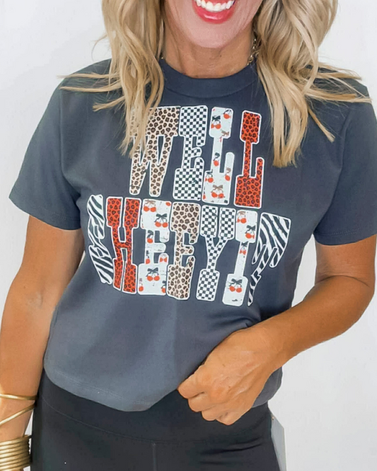 Woman wearing a dark gray t-shirt with colorful graphic design on a plain background