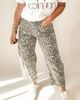 Person wearing a white t-shirt with 'COFFEE' text, leopard print pants, and white sneakers on a light background