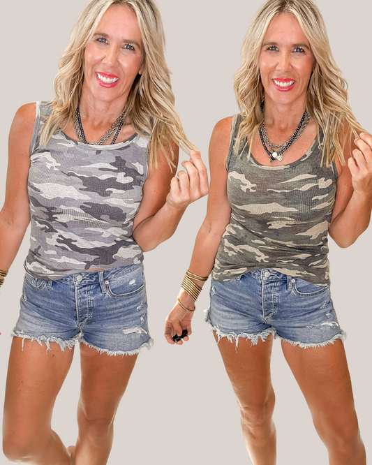 Two identical images of a woman wearing a camouflage tank top in the 2 colors its offerred and denim shorts on a plain background.