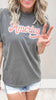 Vintage-style America graphic tee with faded red script and distressed denim shorts.