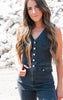 Woman wearing a denim sleeveless jumpsuit standing on a rocky surface.
