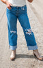 Person wearing blue distressed jeans and brown boots on a concrete surface