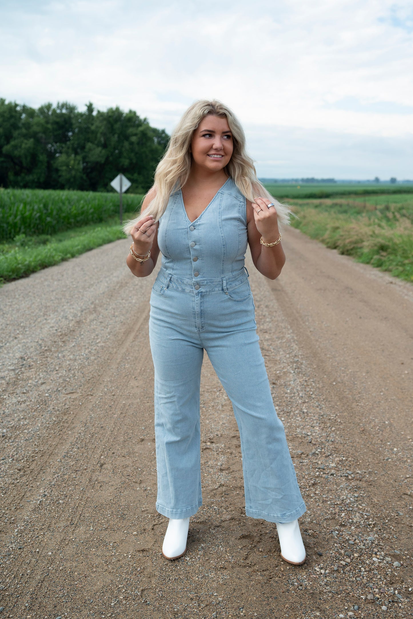 Woman in a light blue jumpsuit standing on a rural road.