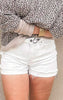 Model wearing MICA white distressed shorts with a button fly and raw hemline.