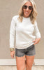 Woman wearing an oatmeal fleece crewneck sweatshirt with front pocket, styled with black frayed denim shorts.