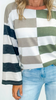 Person wearing a fall striped sweater with long sleeves and blue jeans on a white background