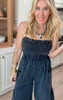 Comfortable and chic black strapless jumpsuit with a gathered top and flowy pant legs, paired with chunky sandals.