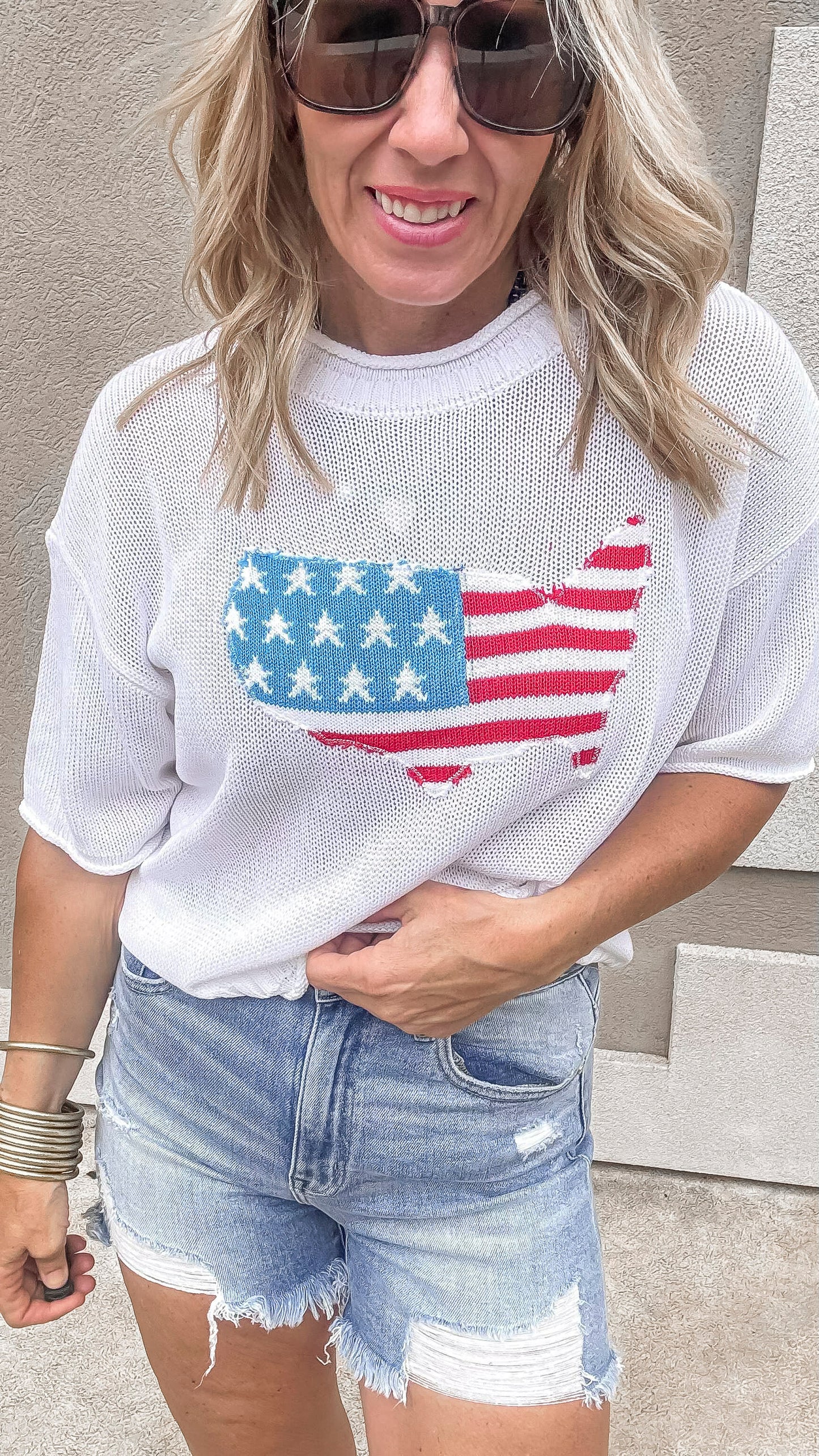 Patriotic flag print sweater paired with frayed denim cutoffs.