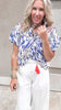 Colorful wanderlust-inspired top styled with white high-waisted pants.