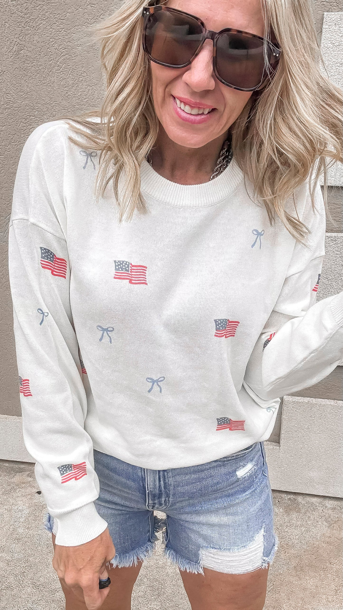 USA flag print sweater with feminine bow details styled with cutoffs.