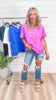 Woman wearing a pink shirt and ripped jeans standing in front of a clothing rack.