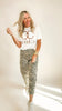 Woman wearing a white t-shirt with text and leopard print pants on a plain background