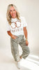 Woman wearing a white t-shirt with a graphic design and leopard print pants on a white background