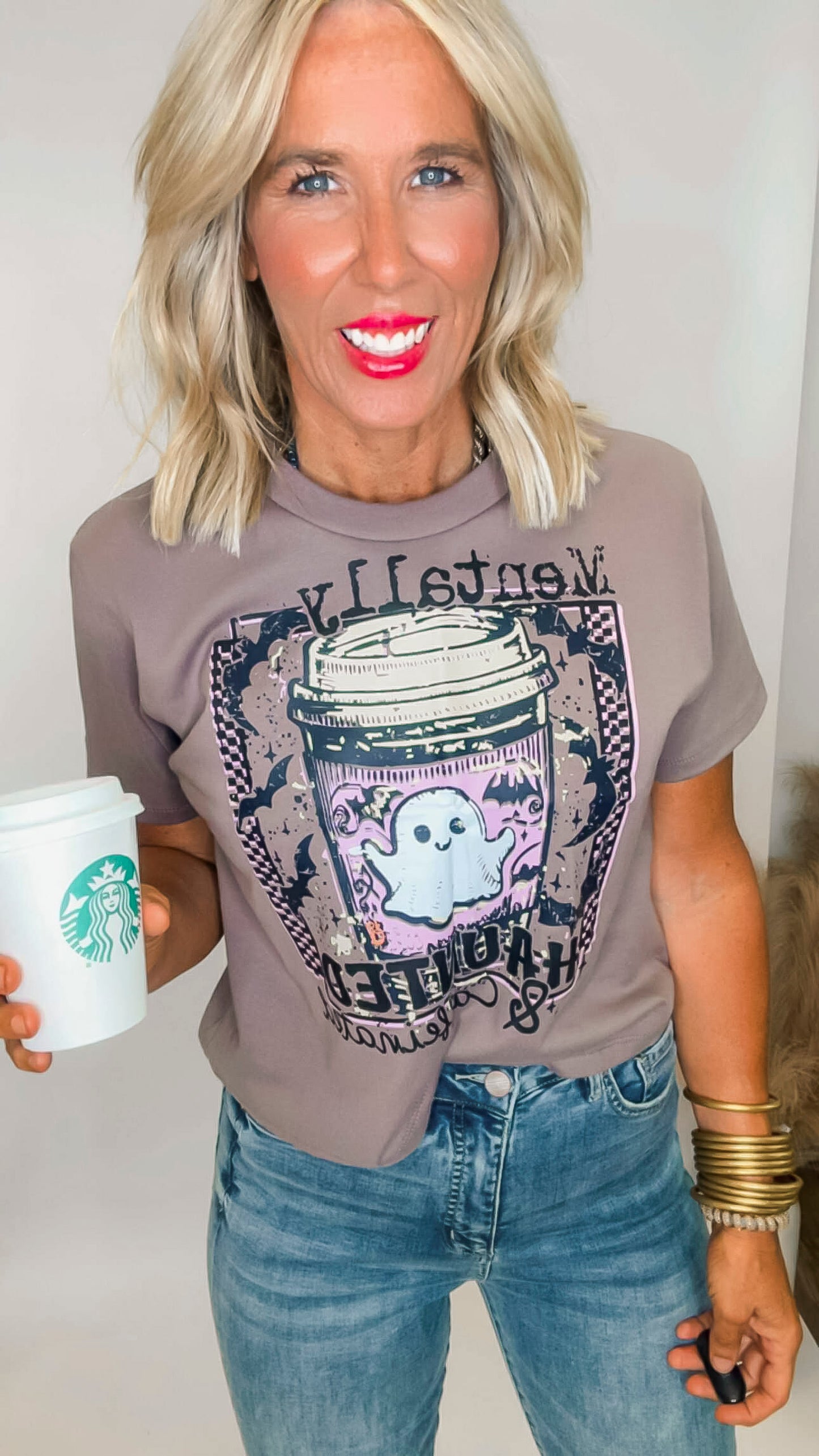 Woman wearing a graphic t-shirt and holding a Starbucks cup.