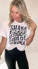 Woman wearing a white t-shirt with 'Shake Shake Senora' text design.