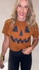 Woman wearing a brown t-shirt with a jack-o'-lantern design on a plain background