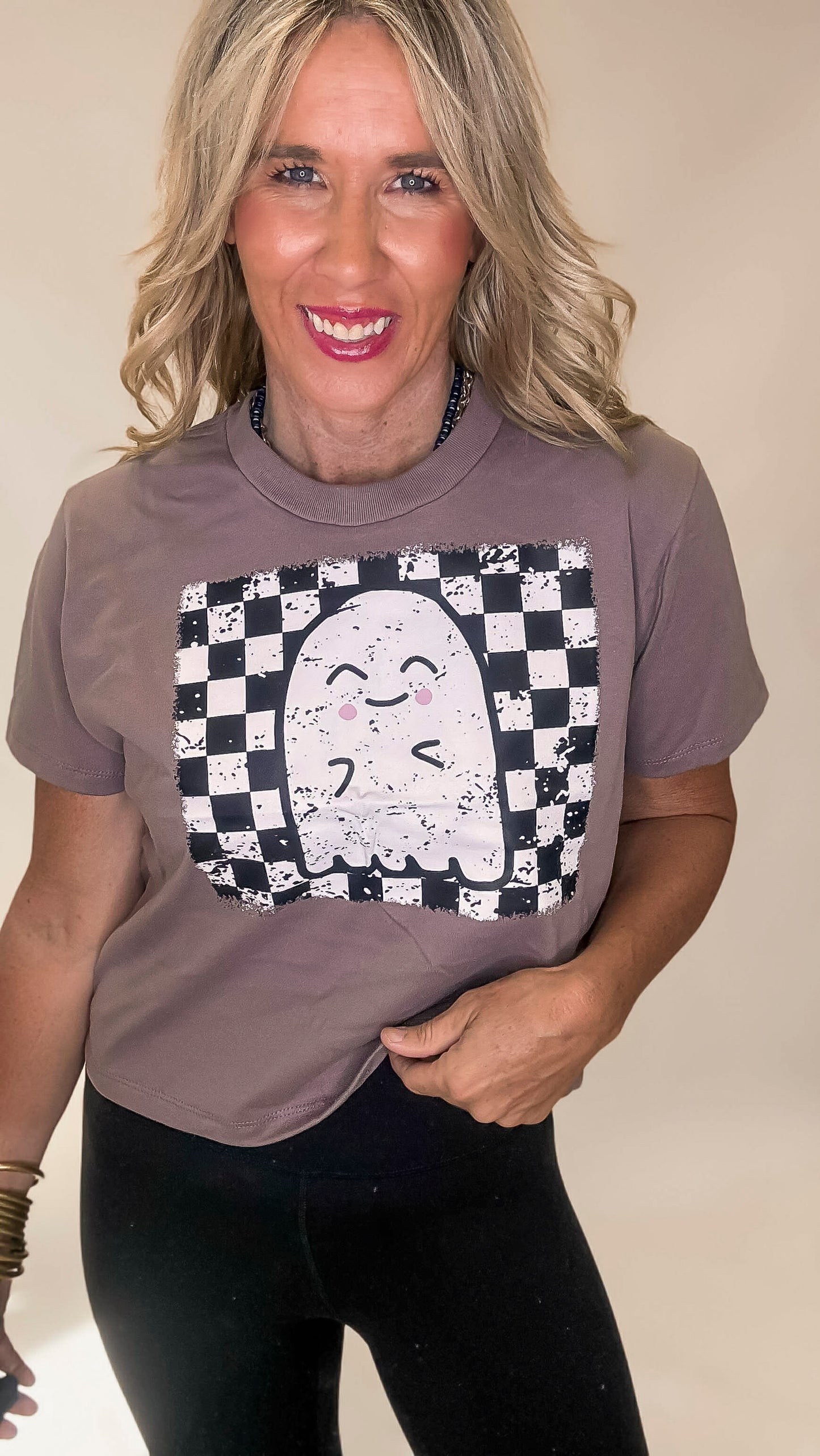 Woman wearing a brown t-shirt with a ghost design on a beige background
