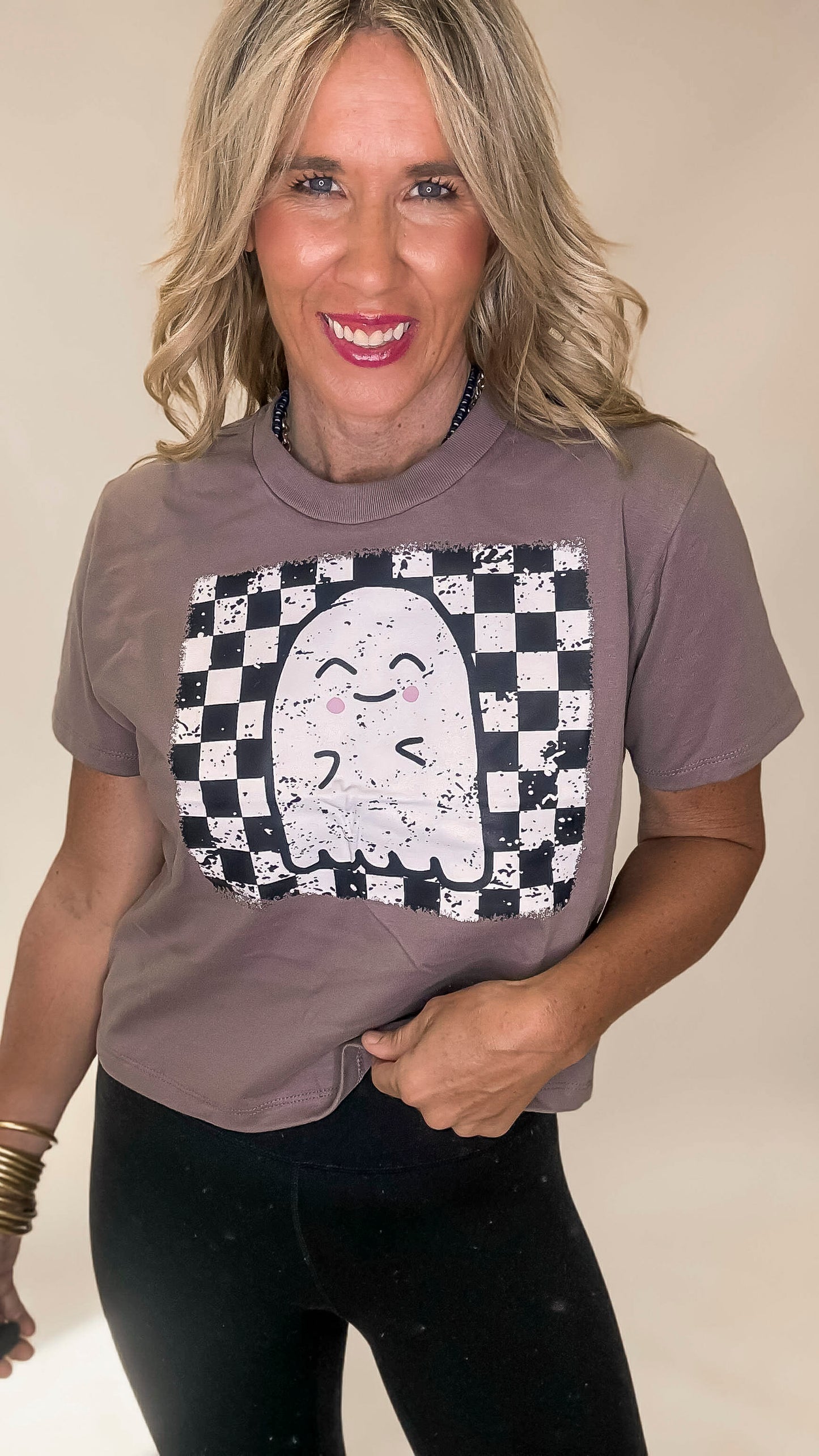 Woman wearing a brown t-shirt with a ghost graphic on a beige background