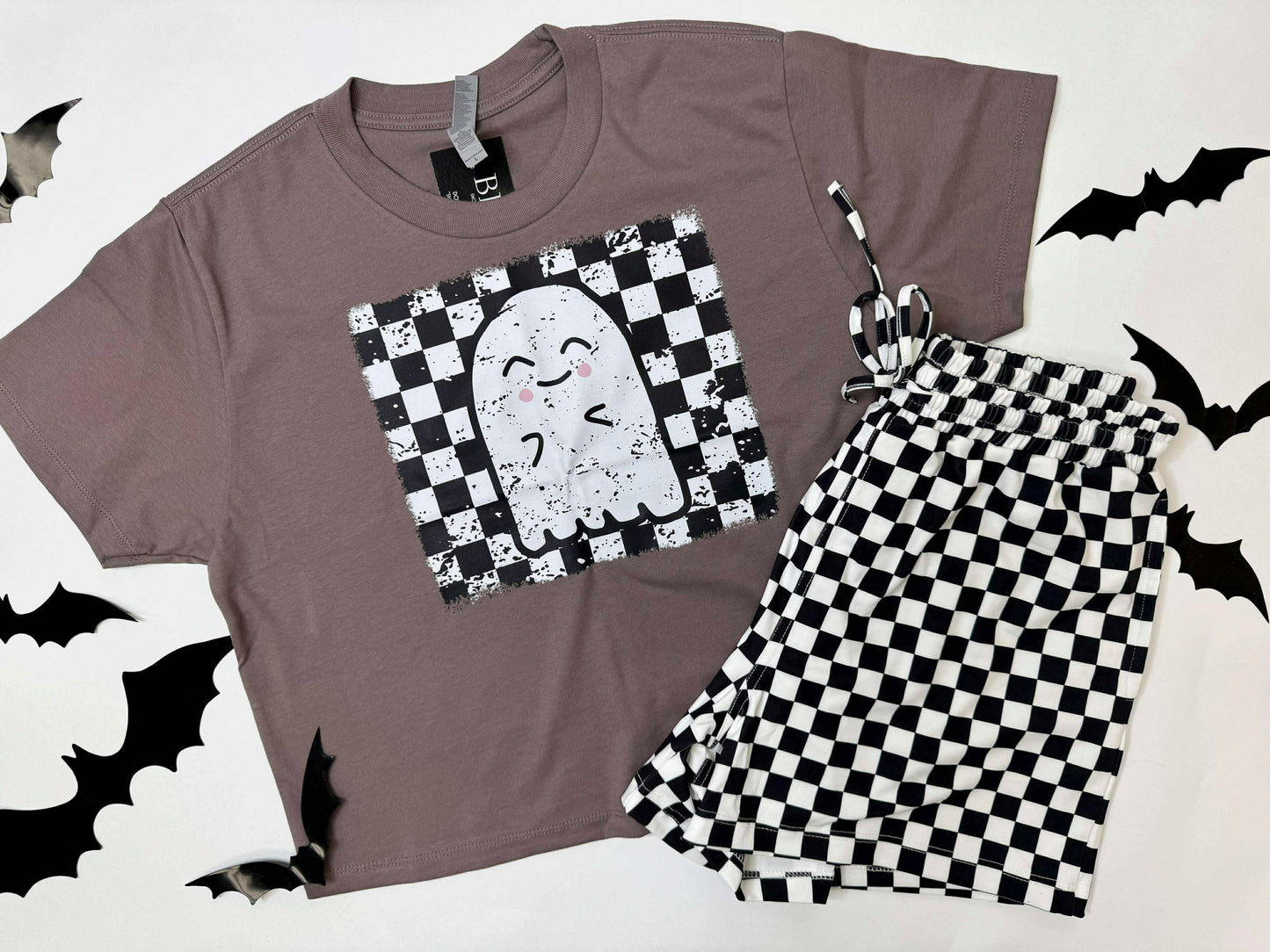 Gray t-shirt with ghost design and checkered shorts on a white background with black bats.