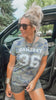 Woman wearing a 'GAMEDAY 36' t-shirt sitting in a car.