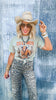 Person wearing a graphic t-shirt with a bull design, leopard print pants, and a cowboy hat against a textured blue background.