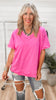 Woman wearing a bright pink oversized shirt and ripped jeans indoors.