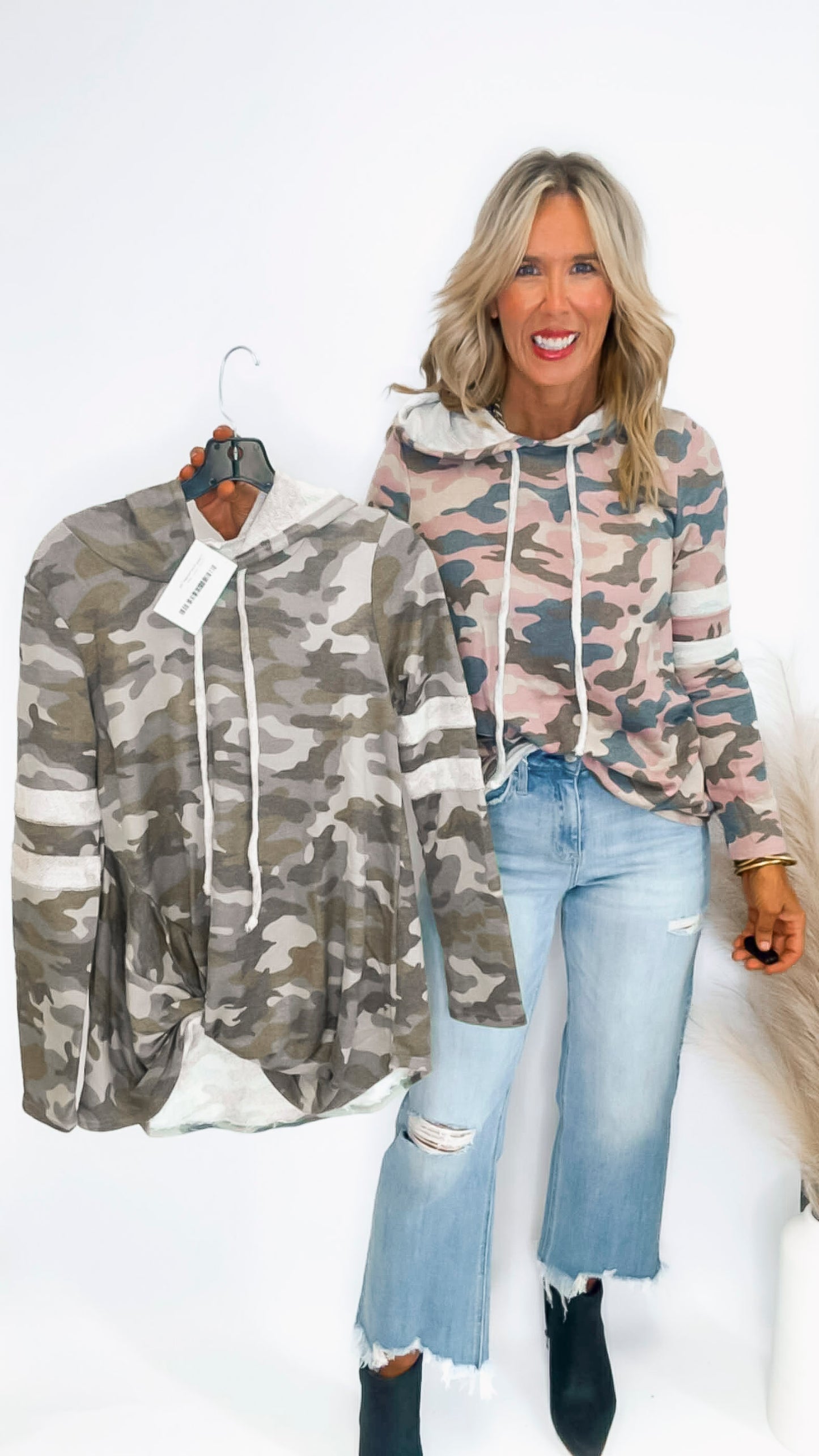 Woman holding a camouflage hoodie with a matching jacket on a white background