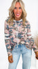 Woman wearing a camouflage hoodie with white drawstrings and light blue jeans on a white background