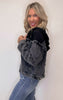 Woman wearing a black denim jacket and blue jeans against a white background