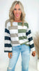 Woman wearing a colorblock stripe long sleeve top and jeans on a white background