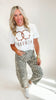 Woman wearing a white t-shirt with text and leopard print pants on a white background