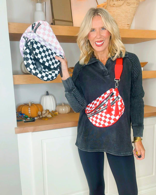 Woman holding a checkered bag with a red strap in a kitchen setting