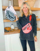 Woman holding a checkered bag with a red strap in a kitchen setting