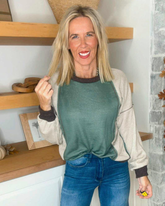 Woman wearing a green and beige sweater with blue jeans indoors.