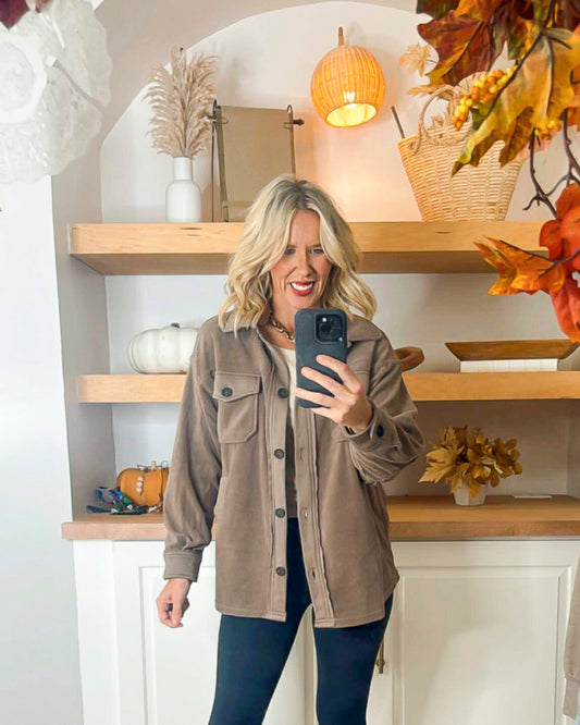Woman taking a selfie in a beige jacket with autumn decorations in the background