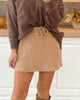 Person wearing a brown sweater and beige skirt in a kitchen setting