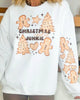 White sweatshirt with Christmas-themed graphics and text worn by a person.