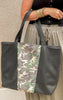 Camo and black weekender tote bag shown with neutral casual outfit, part of the Makeup Junkie & Bad Habit collab.