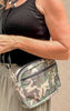 Close-up of camo print Uptown bag with black strap, styled with casual neutral summer outfit.